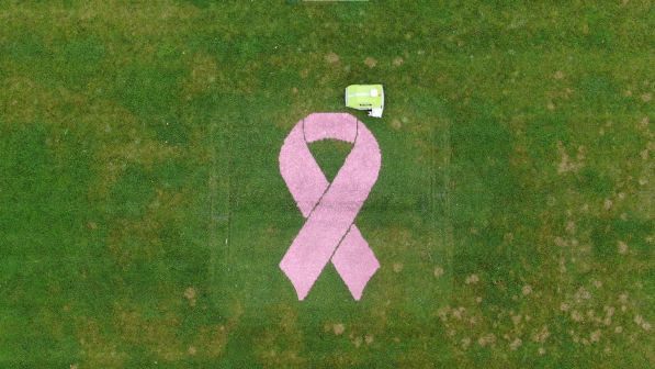 Pink Cancer ribbon painted on a natural grass field by a Turf Tank One Plus robot