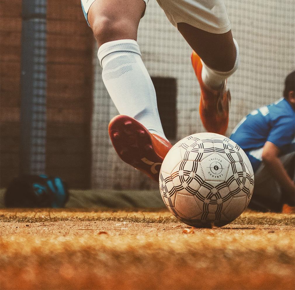 Soccer player with orange boots about to kick a ball